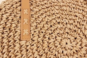 Detail of hand-woven paper rope texture and reinforced leather strap with X-shaped stitching