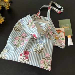 Detail of floral block print tote bag featuring blue stripes and pink flower patterns