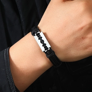 Detail eines Punk-Lederarmbands mit silbernem Rasierklingen-Anhänger am Handgelenk