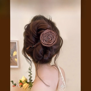 Détail d'une pince à cheveux rose en tissu marron rétro français portée sur un chignon
