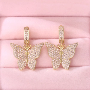 Close-up of gold butterfly earrings with pink cubic zirconia in a velvet box