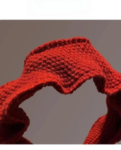 Close-up of red knitted headband showing delicate handmade crochet texture and stitch detail