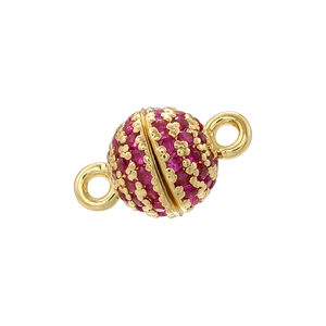 Macro shot of a golden spherical magnetic clasp with red crystals and double loops