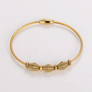 Detailed macro view of golden wire cable bracelet featuring three spiral coil beads