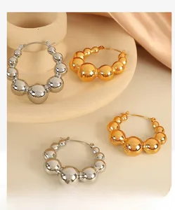 Detailed close-up of gradient gold and silver metallic bead hoop earrings on silk