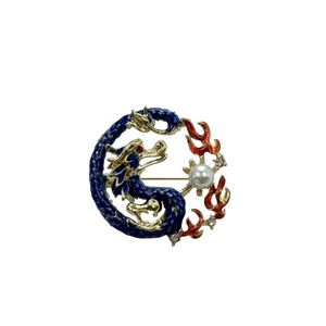 Detailed close-up of blue enamel dragon brooch with pearl accent and gold-plated finish