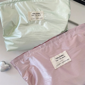 Close-up of lightweight drawstring organizers in glossy green and pink with logo detail