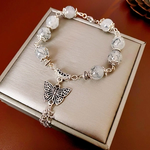 Détail du pendentif papillon et perles de marbre sur un bracelet à pompon chinois