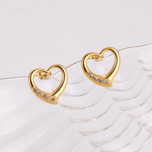 Golden hollow heart stud earrings with six sparkling rhinestones on wavy glass background