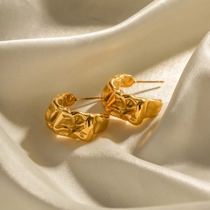 Macro detail of 18k gold plated stainless steel earrings with irregular lava texture