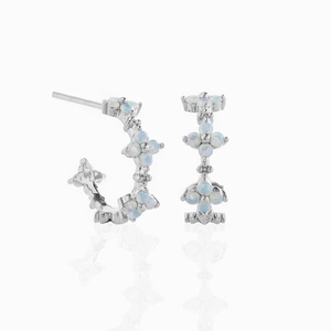 Silver flower stud earrings with blue zircon and white opal stones on white reflection