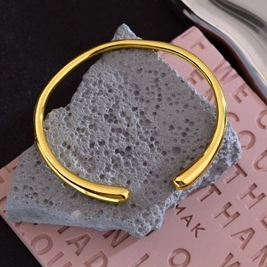 Minimalist golden Rupert tear open bracelet with polished finish on decorative stone base