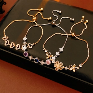 Détail de bracelets ajustables avec cœurs et fleurs en zircon sur support en cuir noir