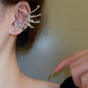 Détail de la bague d'oreille en argent avec cristaux verts sur un mannequin femme