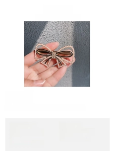 Detail shot of pearl bow hair clip with dimensions 6.4cm by 3.4cm and alloy base