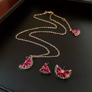 Macro shot of watermelon jewelry set with red and green stones on black leather