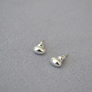 Macro shot of silver polished oval bean earrings on textured grey background