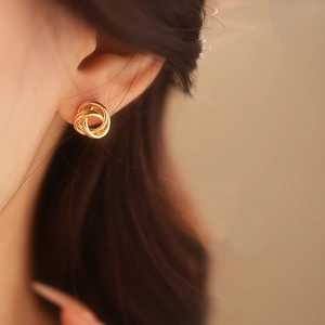 Gros plan d'une boucle d'oreille créole torsadée en or portée par un mannequin, style chic