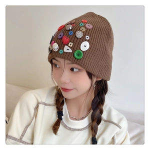 Detail view of brown knit beanie featuring colorful buttons and a red heart accent