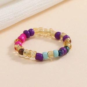 Dettaglio di anello elastico con perline colorate miste su fondo beige in stile boho-chic