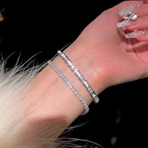 Detail van zilveren slangenarmband en tennisarmband in laagjes om de pols