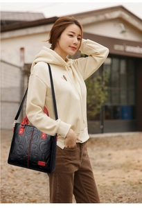 Detail of black embossed leather handbag with red handle and Comfort lettering