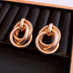 Detailed close-up of golden irregular triple-linked knot earrings with matte texture