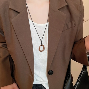 Détail d'un pendentif géométrique irrégulier marron sur un collier à cordon noir