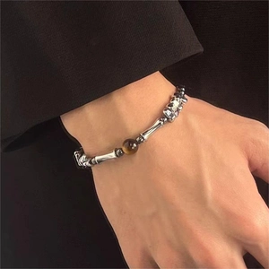 Vista macro di un bracciale a catena con teschio e pietra occhio di tigre sul polso