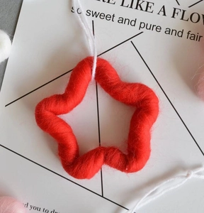 Detail of red wool felt star ornament with plush texture and white hanging string
