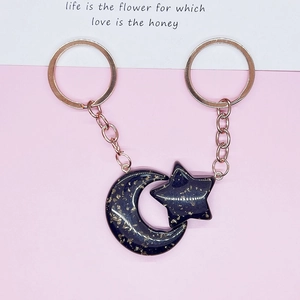 Close-up of glittery dark blue moon and star acrylic keychain with rose gold metal chain