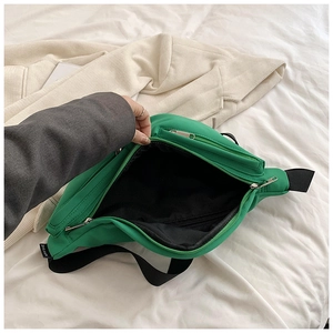 Detail view of green crossbody bag showing multi-layer black interior lining and zippers