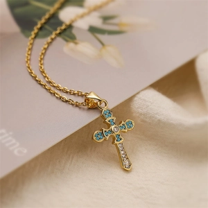 Close-up of gold cross necklace with turquoise and zircon stones on a soft fabric
