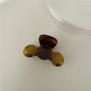 Close-up of small amber hair claw clip on a minimalist beige surface background