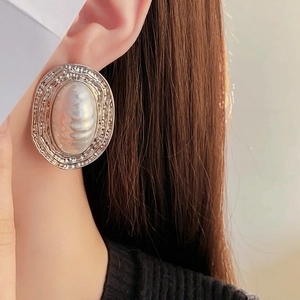 Detail of silver textured oval earrings with pearls worn by a model in close-up