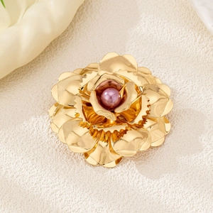 Detailed close-up of a golden multi-petal flower brooch with a pink pearl center