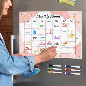 Detailed close-up of a woman writing on a pink magnetic monthly planner with a dry erase marker