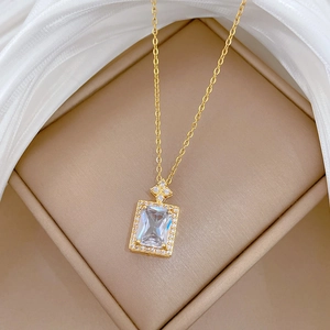 Macro shot of gold square zircon pendant with shimmering crystals on beige silk