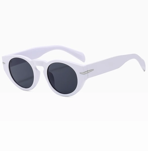 Detail of white round frame sunglasses with silver arrow metal accent and dark lenses