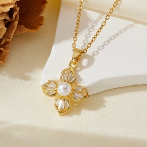 Détail d'un pendentif fleur dorée avec zircons baguettes et une perle blanche