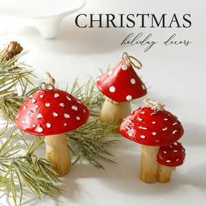 Three red artificial Christmas mushroom ornaments with pine branches on white background