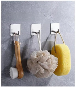 Strong stainless steel adhesive hooks holding a bath brush and sponge on marble wall