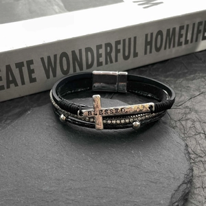 Macro shot of multi-layer braided leather bracelet with a silver BLESSED cross charm