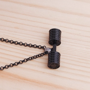 Black dumbbell pendant necklace for fitness lovers on a light wood background