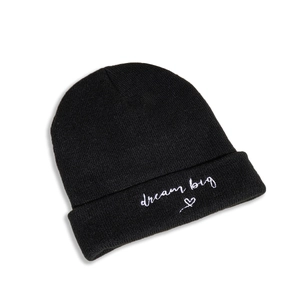 Detail of black knit beanie with white embroidered 'dream big' text and heart pattern
