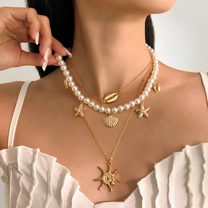 Detail of bohemian layered necklace with white pearls, starfish and shell pendants