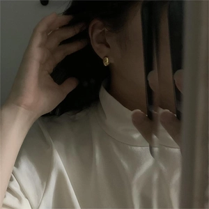 Minimalist small golden oval drop earrings worn in a stylish lifestyle selfie shot