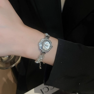 Close-up of a silver floral-shaped watch with crystal inlay on a model's wrist