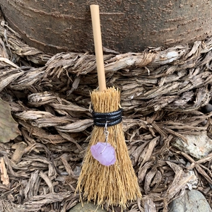 Detailed shot of mini witch broom with pink crystal quartz and natural straw textures