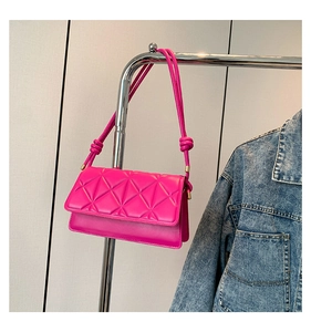 Close-up of fuchsia quilted crossbody bag with knot strap and geometric stitching details